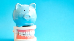 Piggy bank atop model teeth representing the cost of cosmetic dentistry in Toronto