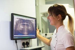Ontario implant dentist smiling while looking at X-rays