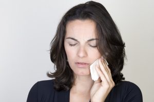 Woman holding cold compress to face