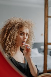 Woman looking in mirror and brushing teeth