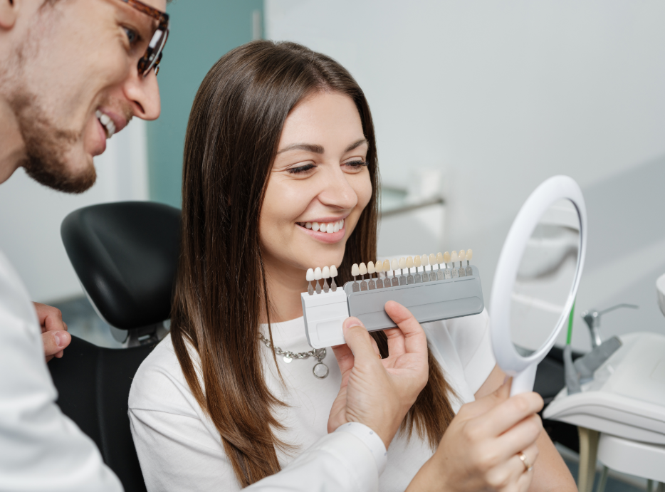 Woman smiling in dental chair while dentist shows her veneers